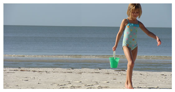 Young girl playing with sand bucket on beach
