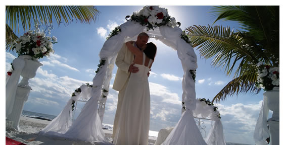 Couple standing under wedding arch on beach